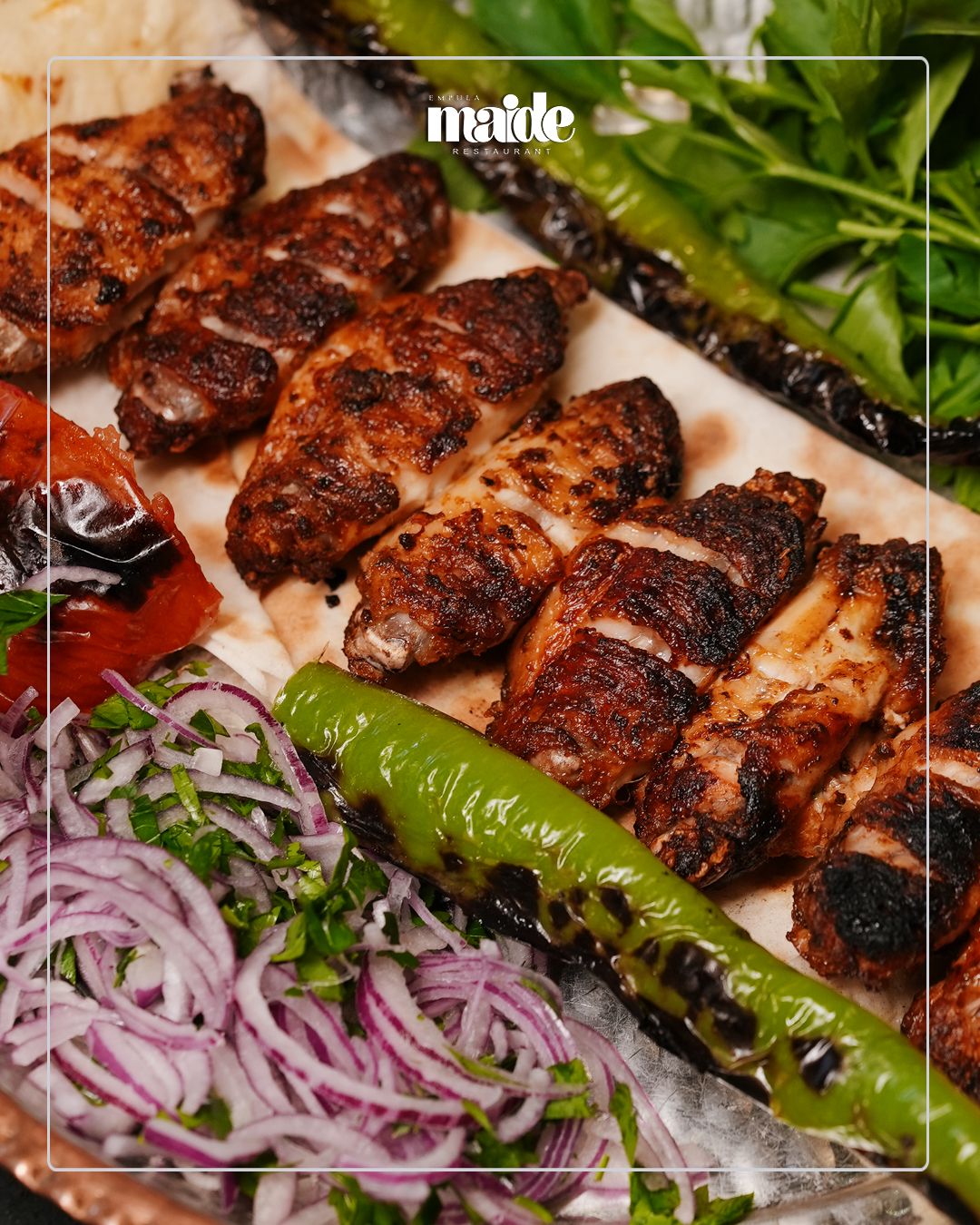 TAVUK KANAT - Özenle marine edilmiş ve ızgarada pişirilmiş Tavuk Kanat, Izgara Domates, Izgara Yeşil Biber, Soğan Piyaz ve Maydanoz eşliğinde servis edilerek sofistike ve aromatik bir ana yemek deneyimi sunar.