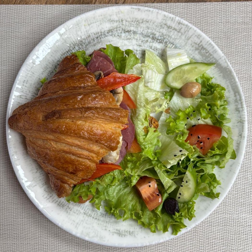 Smoked Meat Sandwich Croissant - Smoked Meat, Acuka (spicy tomato paste), Lettuce, Tomatoes, Roasted Red Peppers, Sautéed Mushrooms; Salad