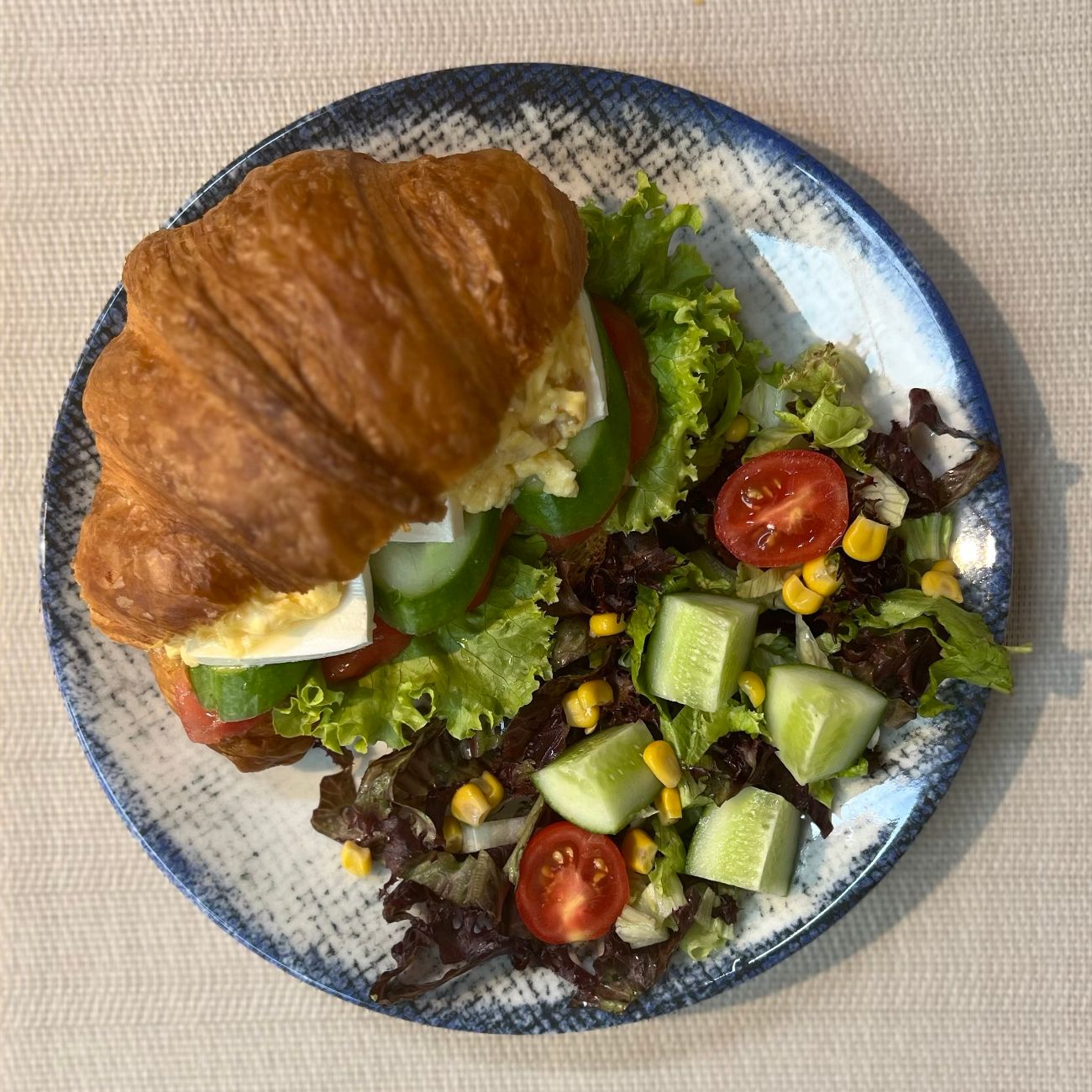 Cheese and Egg Sandwich Croissant - Eggs, cottage cheese, olive paste, tomatoes, cucumbers, lettuce; served with salad.