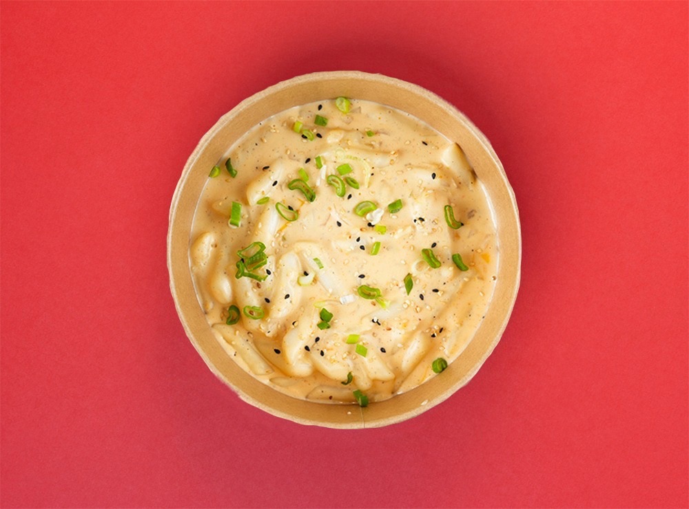 Cheese Topokki - Rice cakes with cream and cheese sauce. Onion, creamy cheddar cheese sauce