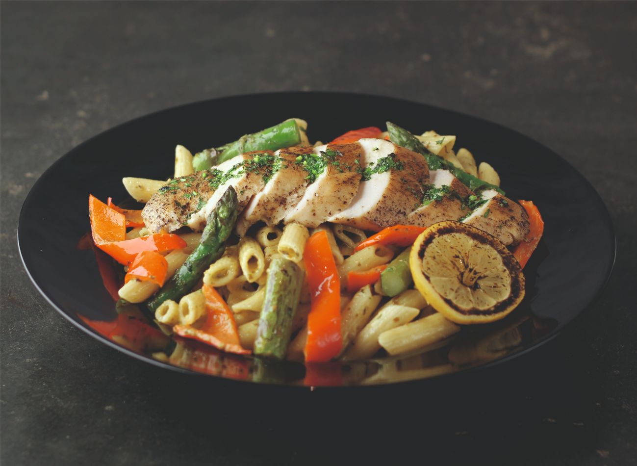 GARLIC LEMON CHICKEN & PESTO PENNE - Sarımsaklı pesto soslu penne makarna, domates, kırmızı biber, yeşil soğan, ızgara kuşkonmaz, bize özgü günlük yapılan morbido peynirimiz ve üzerine sarımsaklı limon soslu ızgara tavuk.