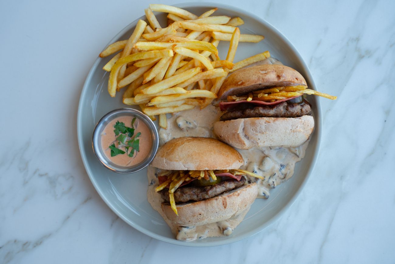 X Burger - Tereyağında kızartılmış burger ekmeği, 150 gr ev yapımı köfte, dana jambon, turşu, cheddar sos, kremalı mantar sos, patates cips ve burger dip sos ile servis edilir.