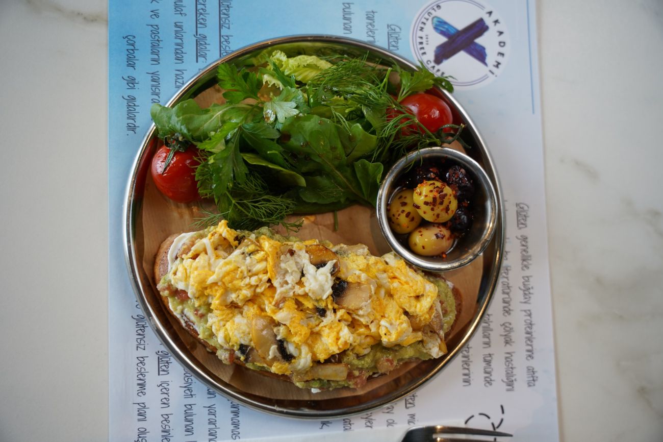 Brunch Royale - El yapımı ekmek dilimi üzerine sürülen labne peyniri, guacamole ve köy peyniriyle hazırlanır; sote mantar ve yumuşak kıvamlı yumurta karışımıyla tamamlanır. Kapari, dereotu, sızma zeytinyağı ve dip sos eşliğinde, taze yeşillik buketiyle servis edilir.
