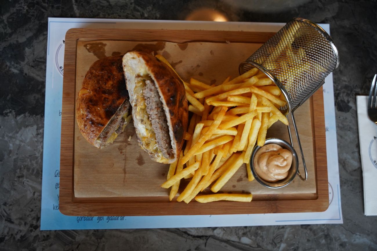 Secret Burger - 1Tereyağında kızartılmış burger ekmeği arasında 150 gr ev yapımı köfte ve 100 gr dana bonfile; cheddar peynir, karamelize soğan ve özel burger dip sos ile hazırlanır. Patates cips ve burger dip sos eşliğinde servis edilir.