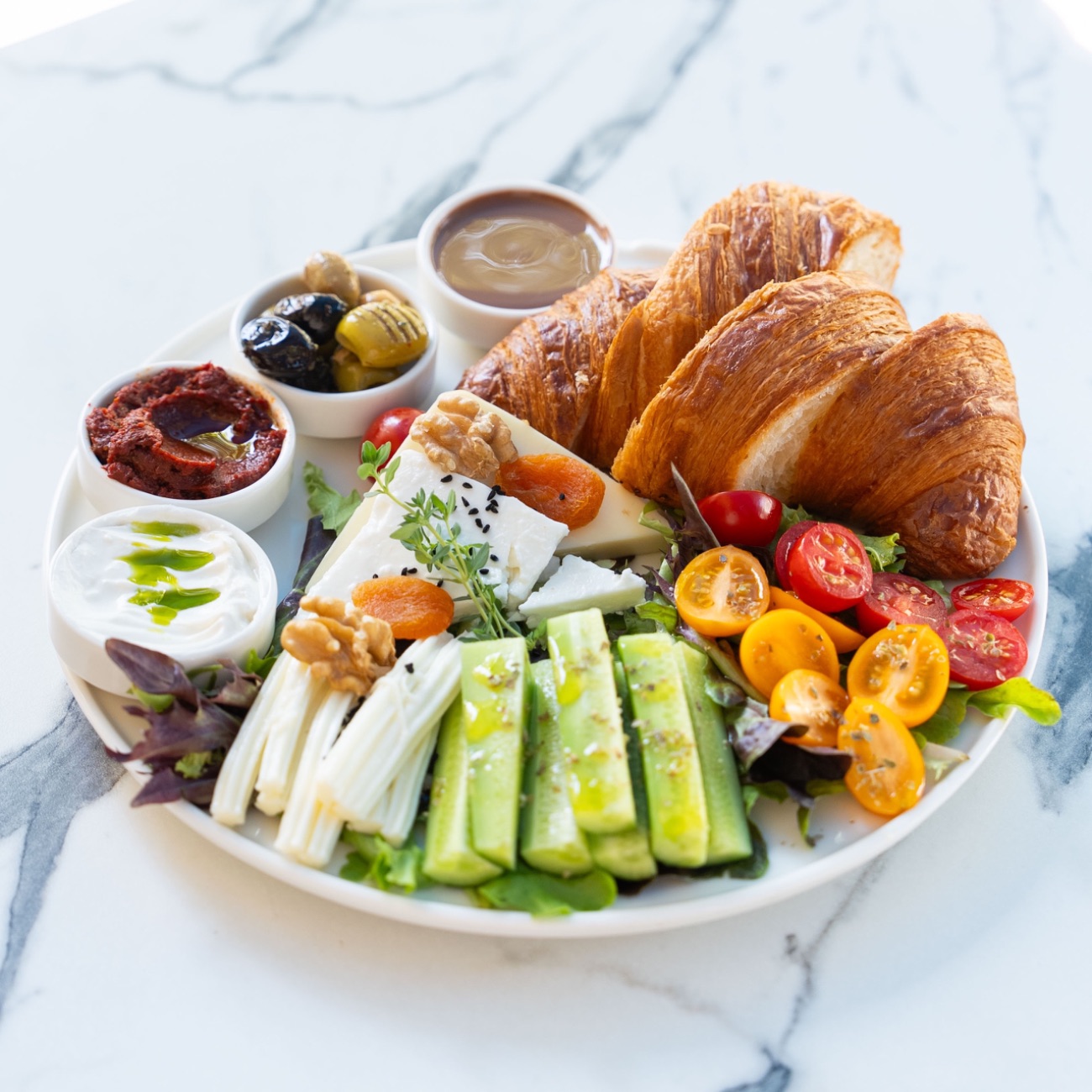 Kruvasan Kahvaltı - Kruvasan, Ezine Peynir, Kaşar Peyniri, Örgü Peynir, Salatalık, Domates, Labne, Acuka, 3 Çeşit Zeytin, Akdeniz Yeşilliği.