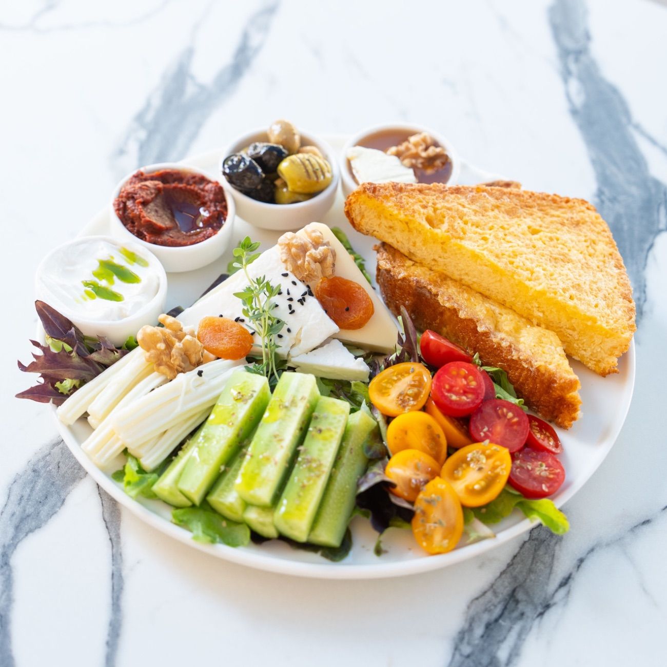 Brioche Kahvaltı - Yumurtayla Kızartılmış Brioche Ekmeği, Ezine Peyniri, Kaşar Peynir, Çeçil Peyniri, Salatalık, Çeri Domates, Labne, Acuka, 3 Çeşit Zeytin, Akdeniz Yeşilliği.