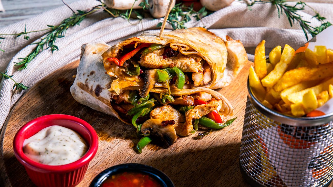 Tavuk Dürüm - Tortilla ekmeği içerisinde,sotelenmiş tavuk parçaları,yeşil biber,kırmızı biber,mantar,kuru soğan,kaşar peyniri,baharatlı patates kızartması,garlıc sos ve sweet chıllı sos ile…