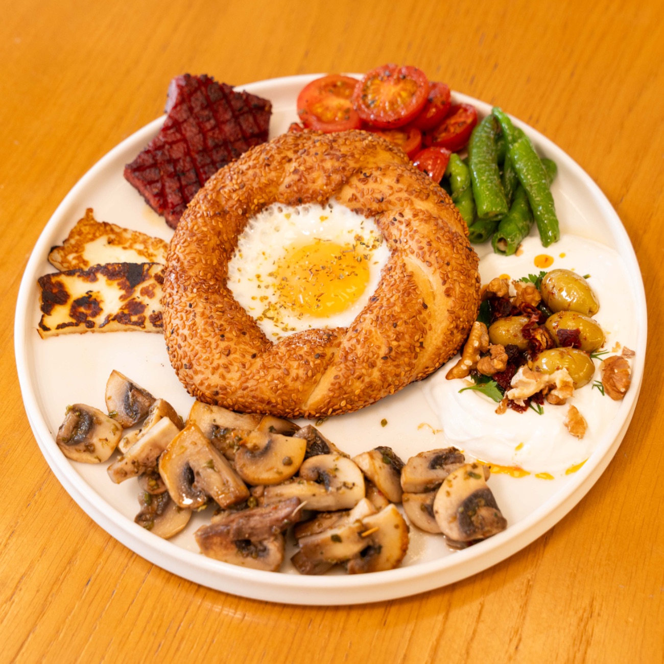 SICAK KAHVALTI TABAĞI - Kangal sucuk, ızgara hellim, sotelenmiş mantar, sotelenmiş kıl biber, sote domates, ekşi krema üzeri zeytin salatası, göz yumurtalı sokak simidi.