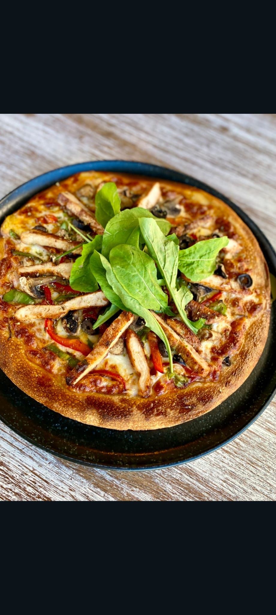 CHICKEN PİZZA - El yapımı pizza hamuru üzerinde,pizza sosu,mozzarella peyniri,ızgara tavuk dilimleri,yeşil biber,kırmızı biber,mantar,dilim siyah zeytin,roka ve kuru kekik ile…