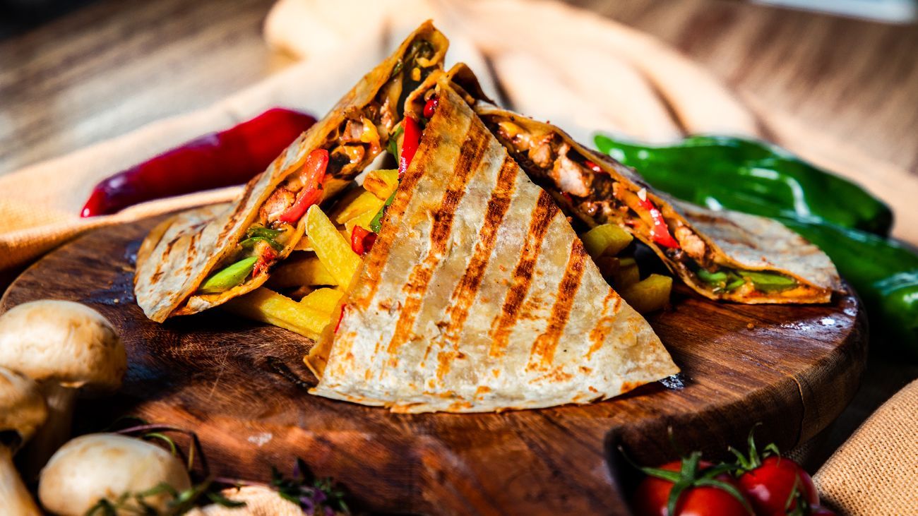 TAVUKLU QUESADILLA - Tortilla ekmeği içerisinde,sotelenmiş tavuk parçaları,yeşil biber,kırmızı biber,mantar,kuru soğan,jalapeno biberi,Meksika fasülyesi,kaşar peyniri,baharatlı patates kızartması,garlıc sos ve sweet chıllı sos ile…