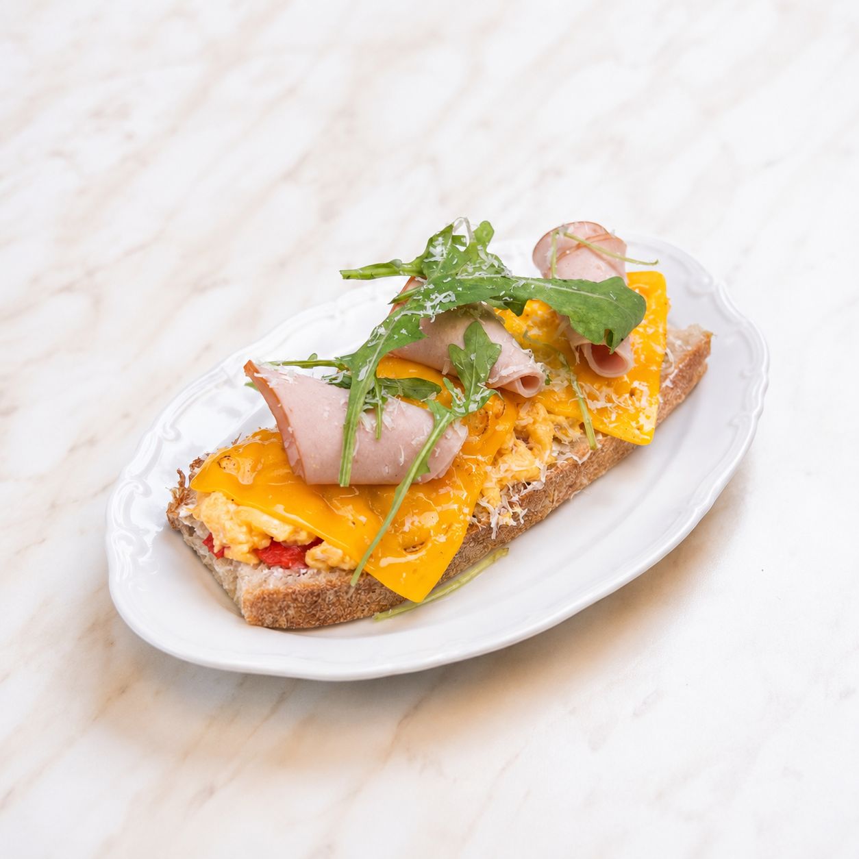 Scrambled Egg Hindi Füme Cheddar Ekmeküstü - Ekşi Mayalı Ekmek, Çırpılmış Yumurta, Hindi Füme, Cheddar Peyniri, Biber, Peynir Sos, Parmesan Peyniri, Rakula.