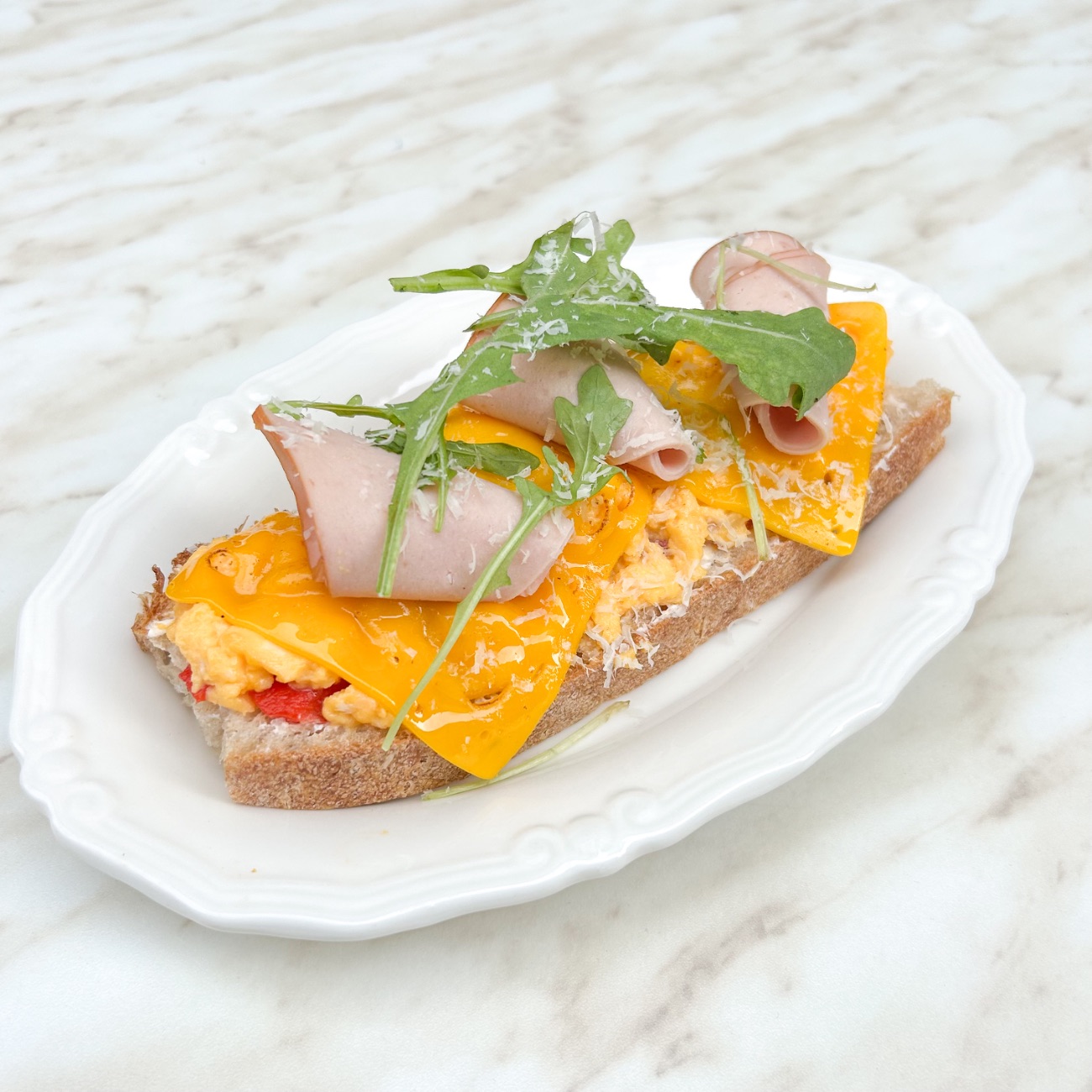 Scrambled Egg Hindi Füme Cheddar Ekmeküstü - Ekşi Mayalı Ekmek, Çırpılmış Yumurta, Hindi Füme, Cheddar Peyniri, Biber, Peynir Sos, Parmesan Peyniri, Rakula.