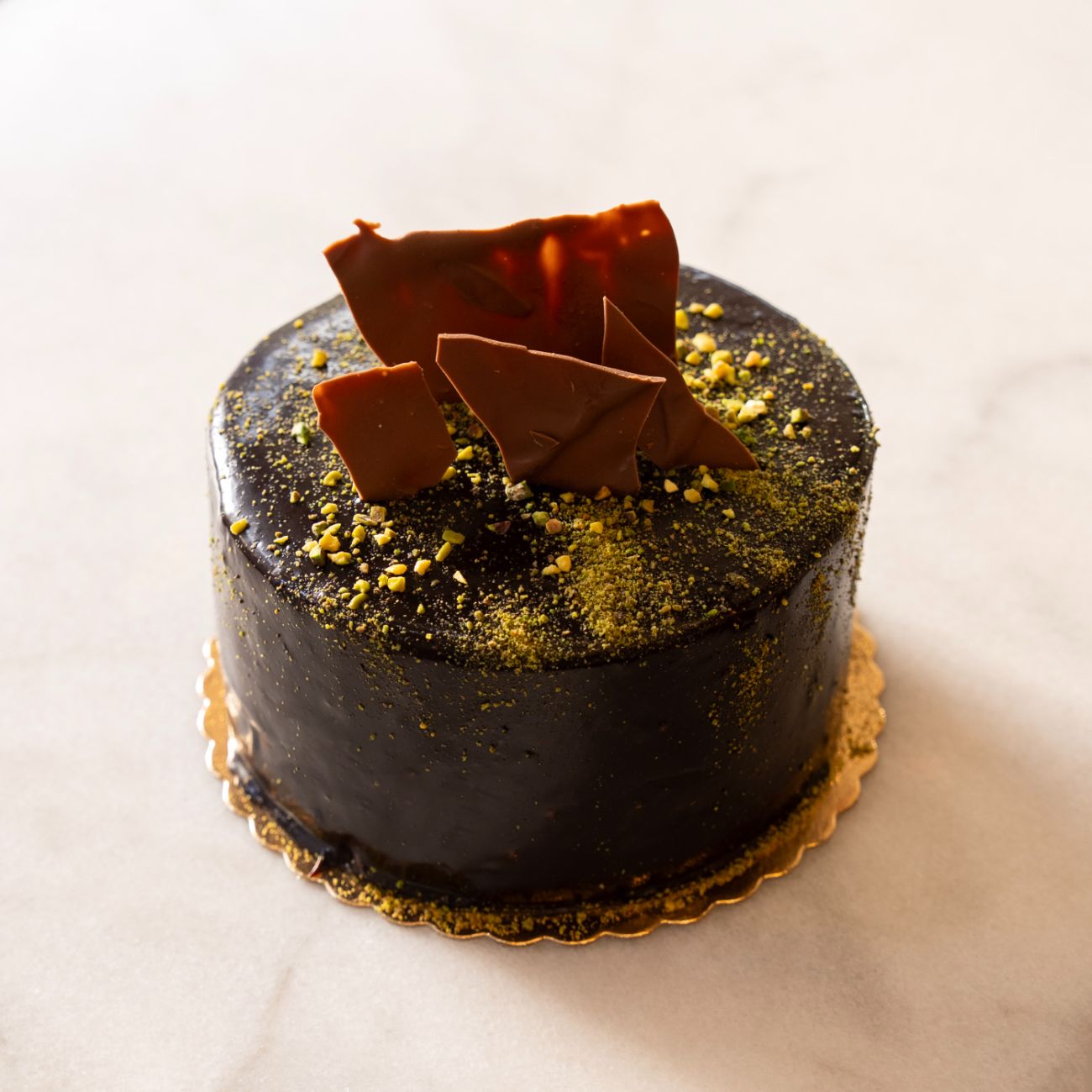 Fıstıklı Pasta (4-6 Kişilik) - Kakaolu pandispanya, pastacı kreması, çikolatalı sos, profiterol sos, bitter çikolatalı Antep fıstığı.