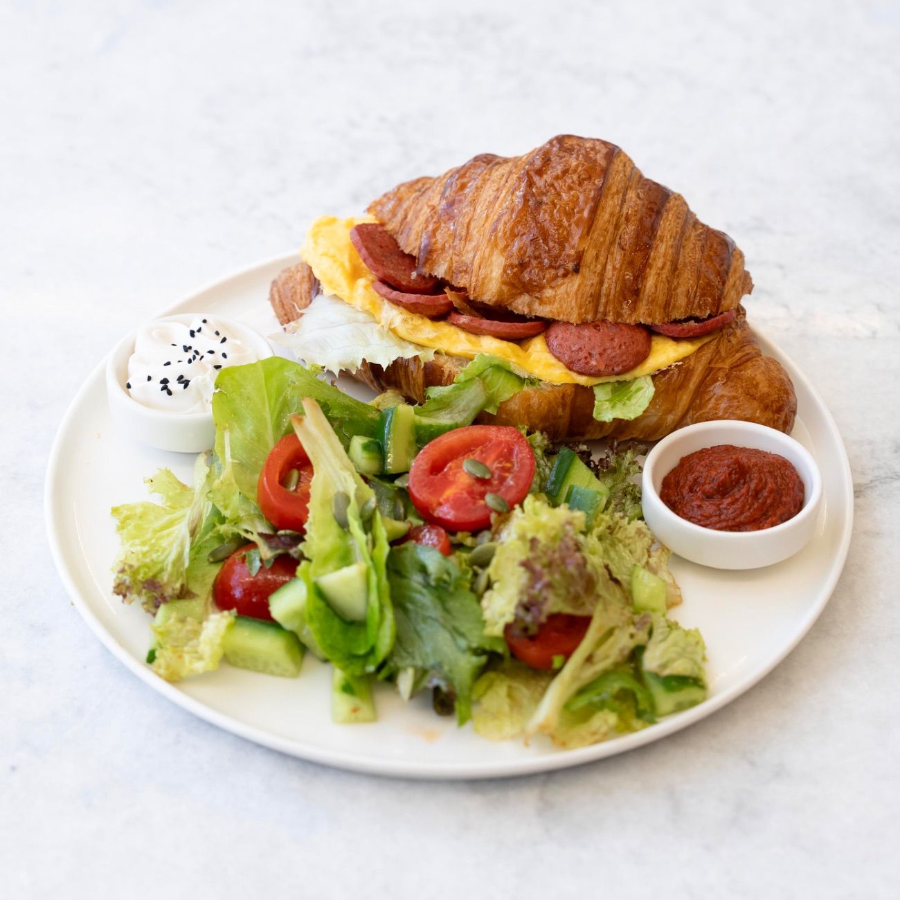 Sucuklu Yumurtalı Kruvasan - Peynir Sos, Marul, Çırpılmış Yumurta, Sucuk. Peynir Sos ve Acuka ile servis edilir.