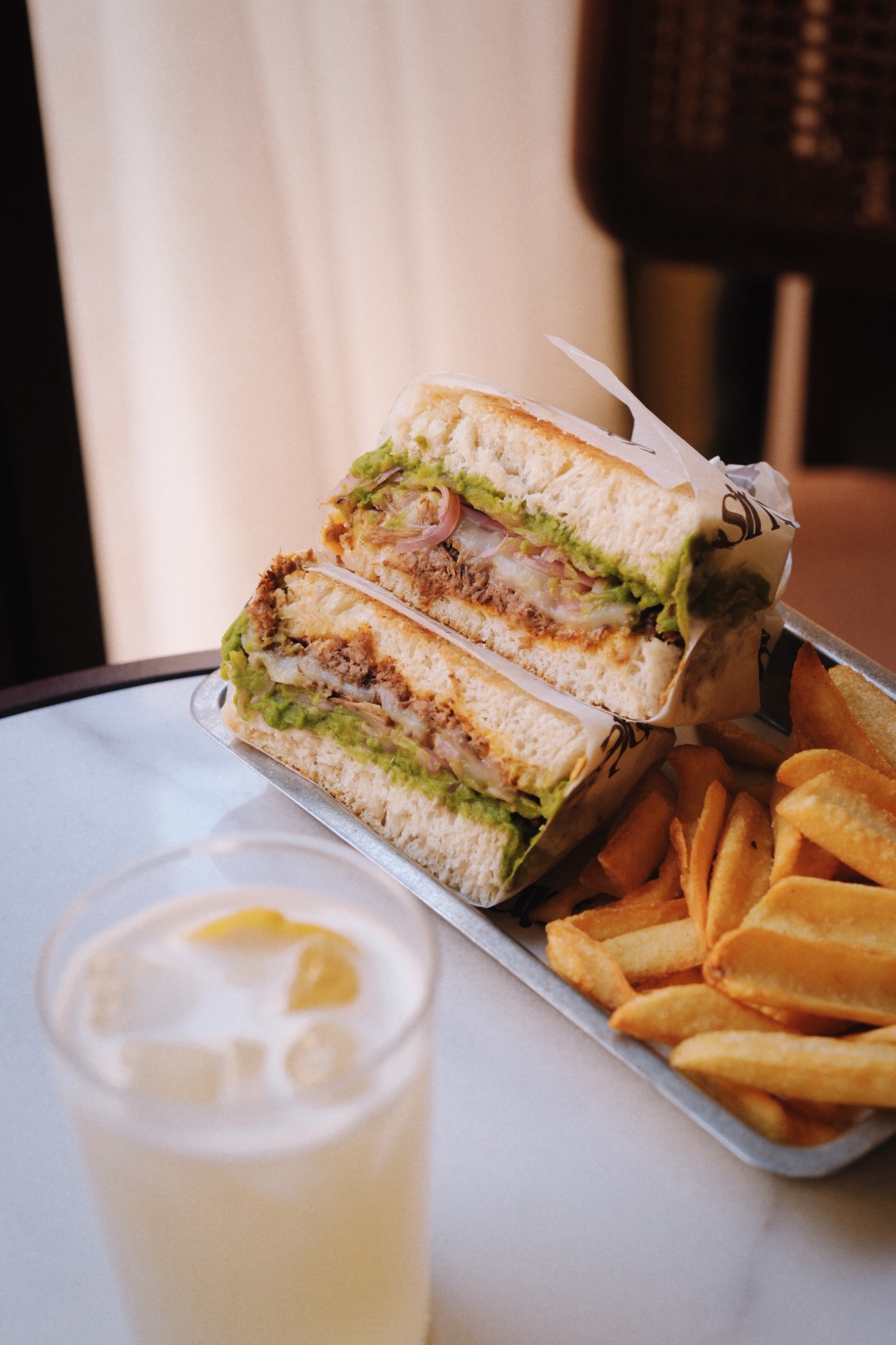 Shredded Meat Sandwich - Homemade toast bread, truffle avocado cream, shredded meat, mozzarella, pickled red onions, spicy cheddar sauce, served with french fries.