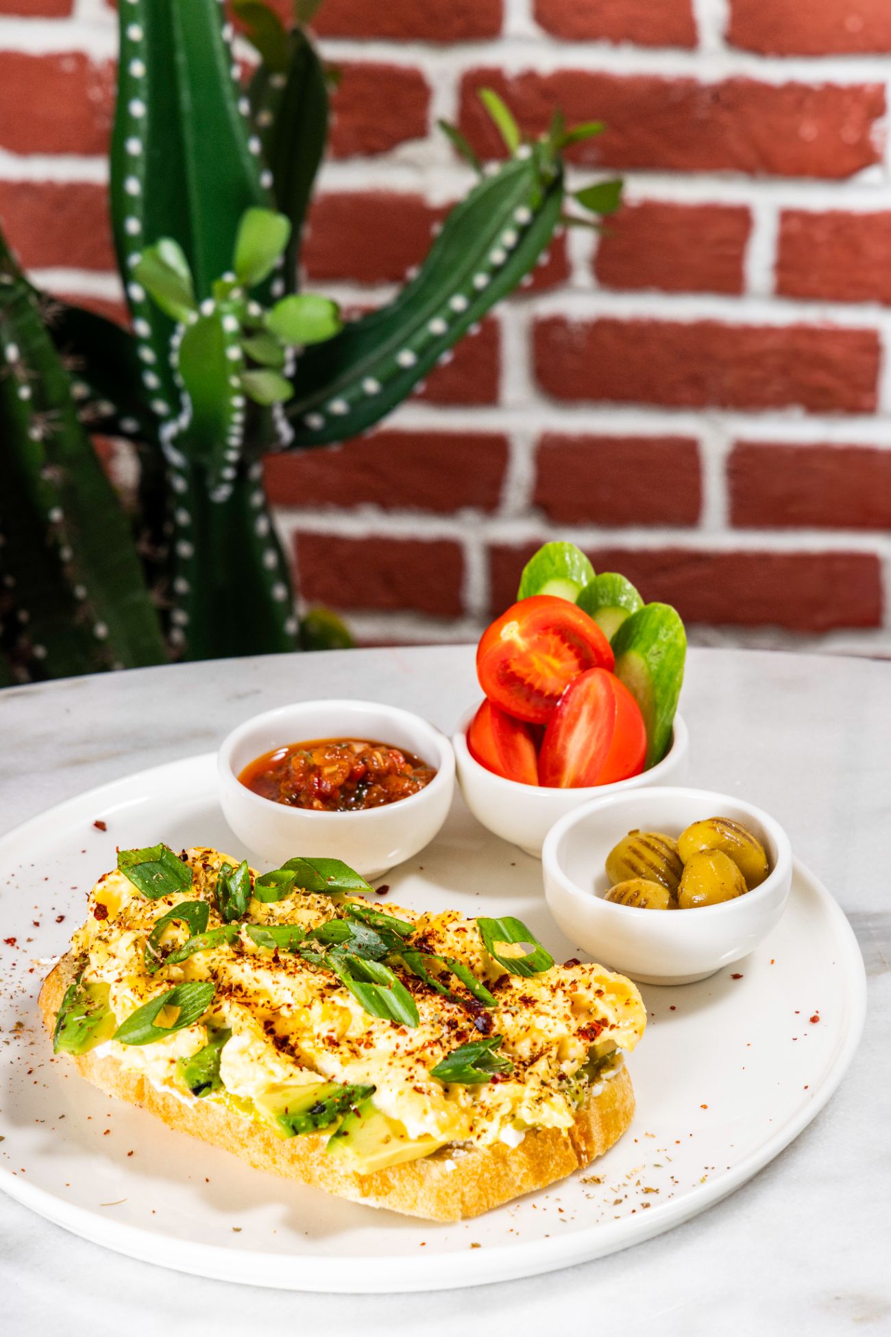 Avokado Tartine - Ekşi mayalı ekmek, krem peyniri, lor peyniri, avokado sos, dilimlenmiş avokado, scrambel yumurta, yeşil soğan, ızgara zeytin, dilimlenmiş domates ve salatalık, patlıcan sosu. Servis süresi min. 20 dk.’dır.