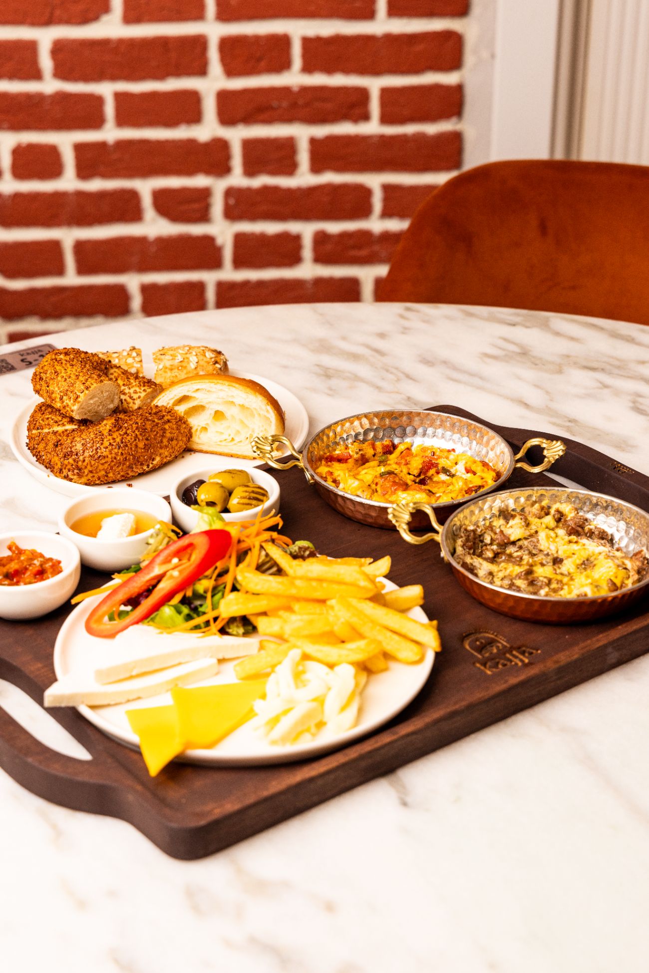 Kajja Select Kahvaltı Tepsisi - Fırından Sahana İmza Kahvaltı "Kahvaltının her detayında el emeği var! Bakır sahanda dumanı üstünde kavurmalı yumurta ve menemen, mutfağımızda günlük hazırlanan çıtır simit, tereyağlı kruvasan ve nefis çavdar ekmeği ile servis ediliyor. Üç çeşit seçkin peynir, iki çeşit zeytin, taptaze bahçe salatası ve çıtır patatese; tamamı el yapımı olan sosumuz ve bal kaymak eşlik ediyor. Servis süresi min. 20 dk.’dır.