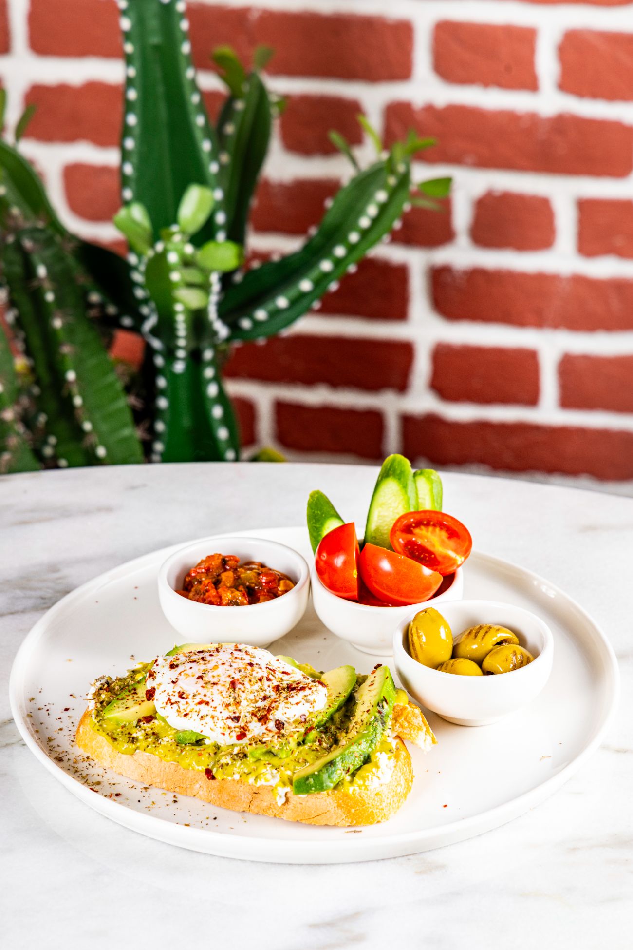 Avokado Poşe Tartine - Ekşi mayalı ekmek, krem peyniri, lor peyniri, avokado sos, dilimlenmiş avokado, poşe yumurta, ızgara zeytin, dilimlenmiş domates ve salatalık, patlıcan sosu. Servis süresi min. 20 dk.’dır.