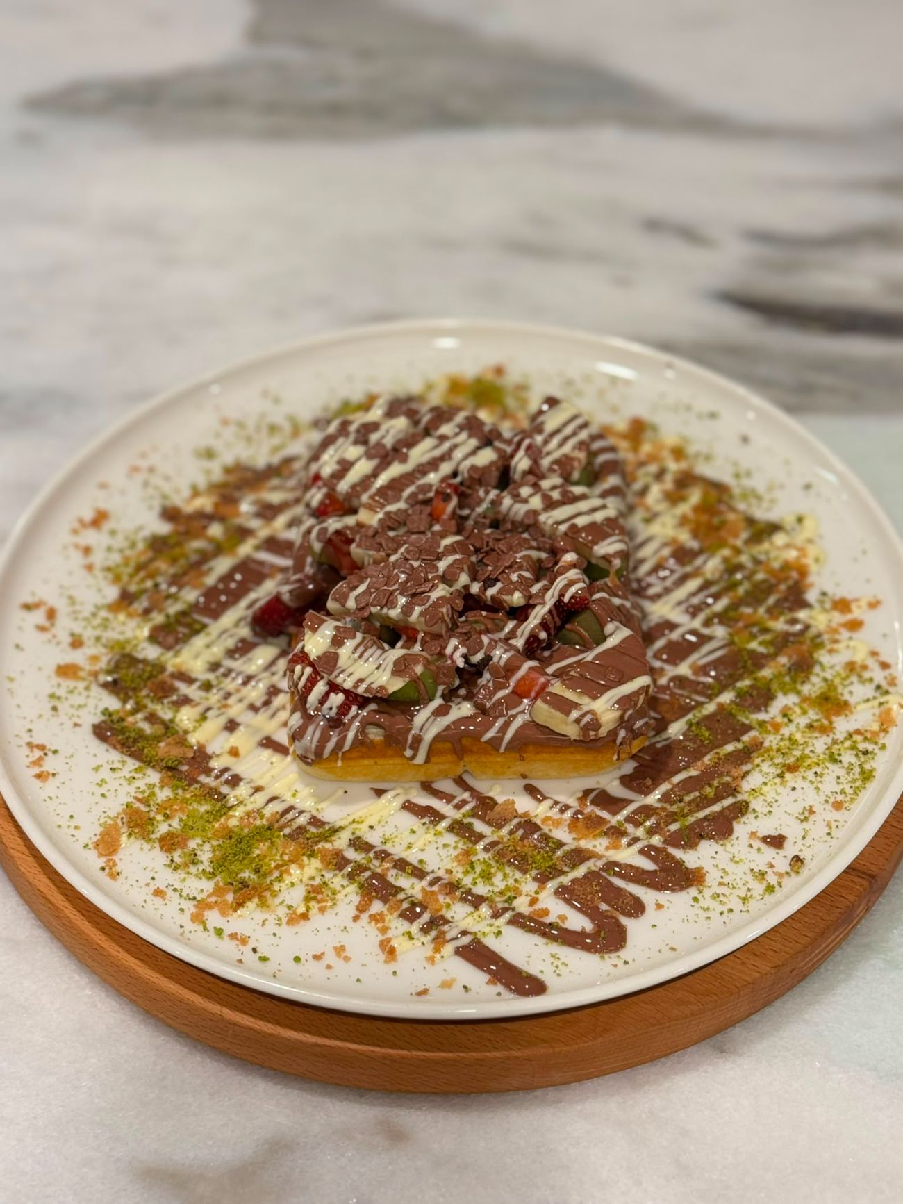 Klasik Waffle - Taptaze çilek, muz ve kivinin ferahlığını, enfes Belçika çikolatasının yoğun lezzetiyle buluşturduk. Dışı çıtır, içi yumuşacık waffle'ımız her lokmada meyvenin tazeliğini ve çikolatanın eşsiz tadını bir araya getiriyor. Kendinizi bu lezzet şöleniyle şımartın!