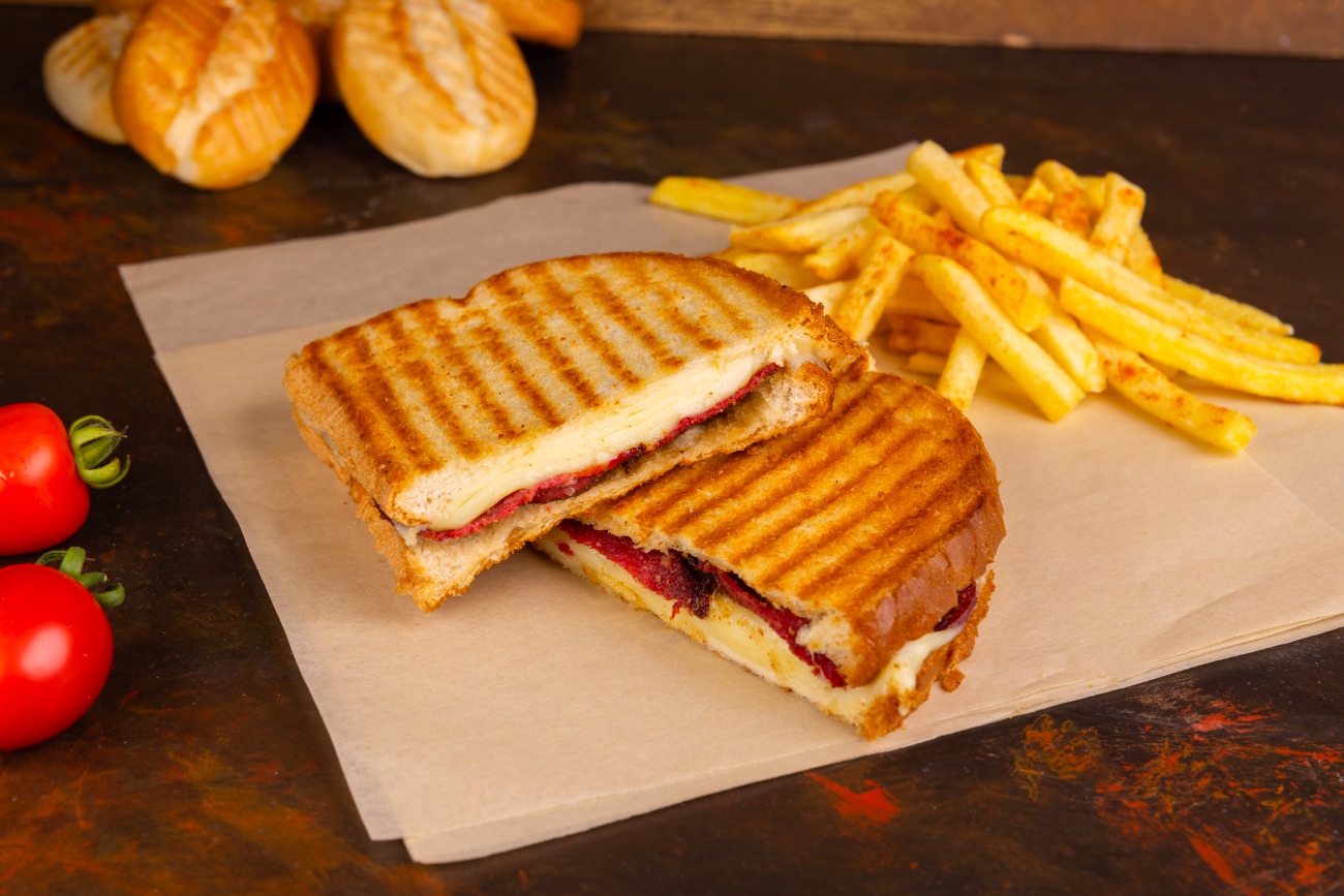 Ayvalık Tostu - Geleneksel sunumuyla tereyağlı ekmek arasına kaşar ve sucuk. Yanında cips ile.