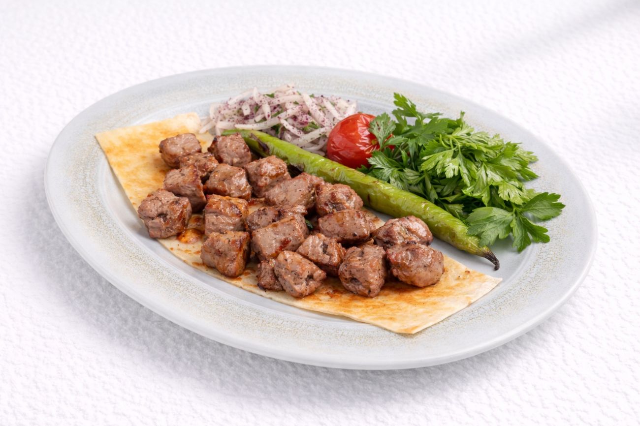 Kuzu Şi̇ş - Sumaklı soğan, köz domates ve köz biber ile servis edilir.