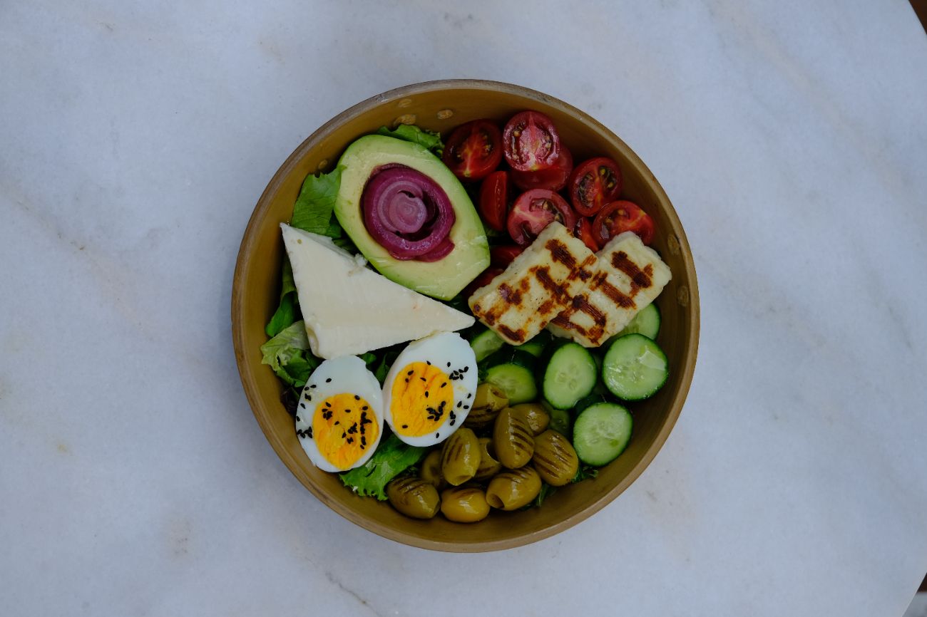 Vejetaryen Kase - Akdeniz yeşillikleri üzerinde haşlanmış yumurta, ezine peyniri, ızgara hellim, avokado, kırmızı soğan turşusu, domates, salatalık, ızgara yeşil zeytin