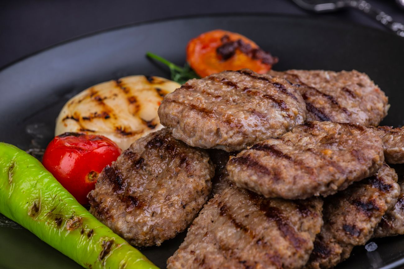 Akçaabat Köfte 1,5 Porsiyon - Geleneksel Akçaabat Köftesi (9 adet), kızarmış biber, domates ve meze ile birlikte servis edilir.