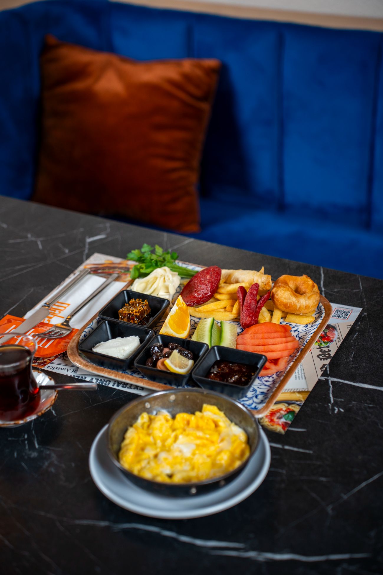 Tabak Kahvaltı - Bal Kaymak, Reçel, Çemen, Karışık Zeytin, Ezine, Beyaz, Çeçil Peyniri, Domates, Salatalık, Yeşillik, Meyve, Patates, Pişi, Sosis, Sucuk, Çırpılmış Yumurta, 2 adet çay