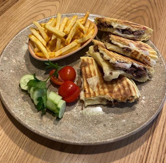 Kavurmalı Tost - Özel bazlama ekmeği arasında dana kavurma, taze dil peyniri yanında yeşillik ve baharatlı parmak patates