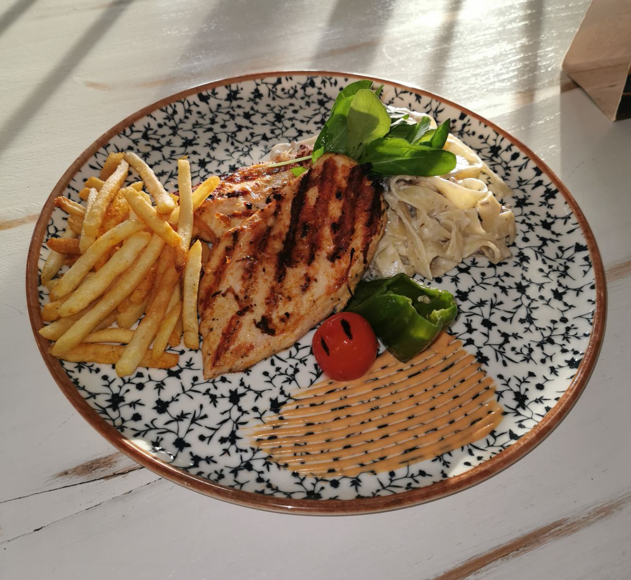 Tavuk Külbastı - Dağ kekiği, pul biber, taze baharatlarla marine edilmiş tavuk bonfile, ızgara domates ve biber, yanında mantar soslu taglıatelle , baharatlı parmak patates