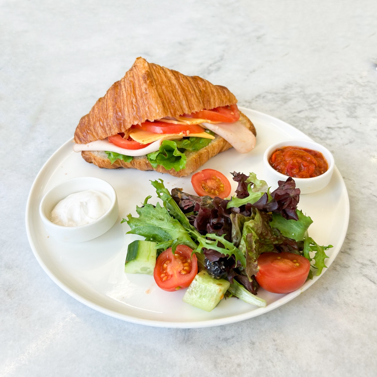 Hindi Füme Cheddarlı Kruvasan - Hindi Füme, Peynir Sos, Kıvırcık, Cheddar Peynir, Domates, Akdeniz Yeşillikleri, Çeri Domates, Salatalık, 2 Çeşit Zeytin. Yanında Acuka ve Peynir Sos ile servis edilir.