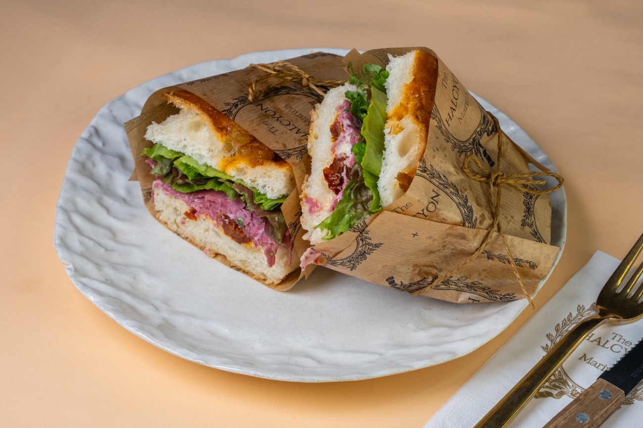 King - Yumuşacık foccacia ekmeğinin arasında füme etin derin aroması, dana kaburganın dolgun lezzetiyle birleşiyor. Tütsü dokunuşu taşıyan özel mayonez, sandviçe bambaşka bir karakter katıyor. Taze roka, domates, lolorosso ve marul ise her ısırığa ferah ve dengeli bir canlılık getiriyor. King, adından da anlaşılacağı gibi güçlü tatların birleşimi; doyurucu, cesur ve gerçek bir kral seçimi. 👑✨