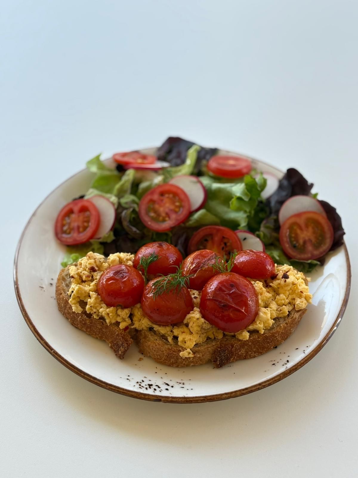 Egg Tartine - Tereyağında kızartılmış ekşi mayalı ekmek, pestolu ricotta sos, screamble yumurta, confit domates, mikro filiz, salata ve yeşil zeytin eşlikçileriyle...