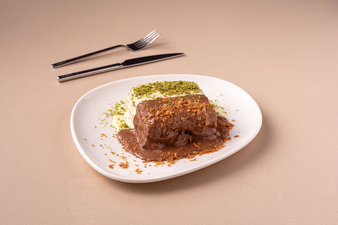 Müzeyyen (Yeni) - iki ince dilim kek, paris kreması, çilek parçacıkları, sütlü ve beyaz çikolata, muz, krep kırığı, antep fıstığı